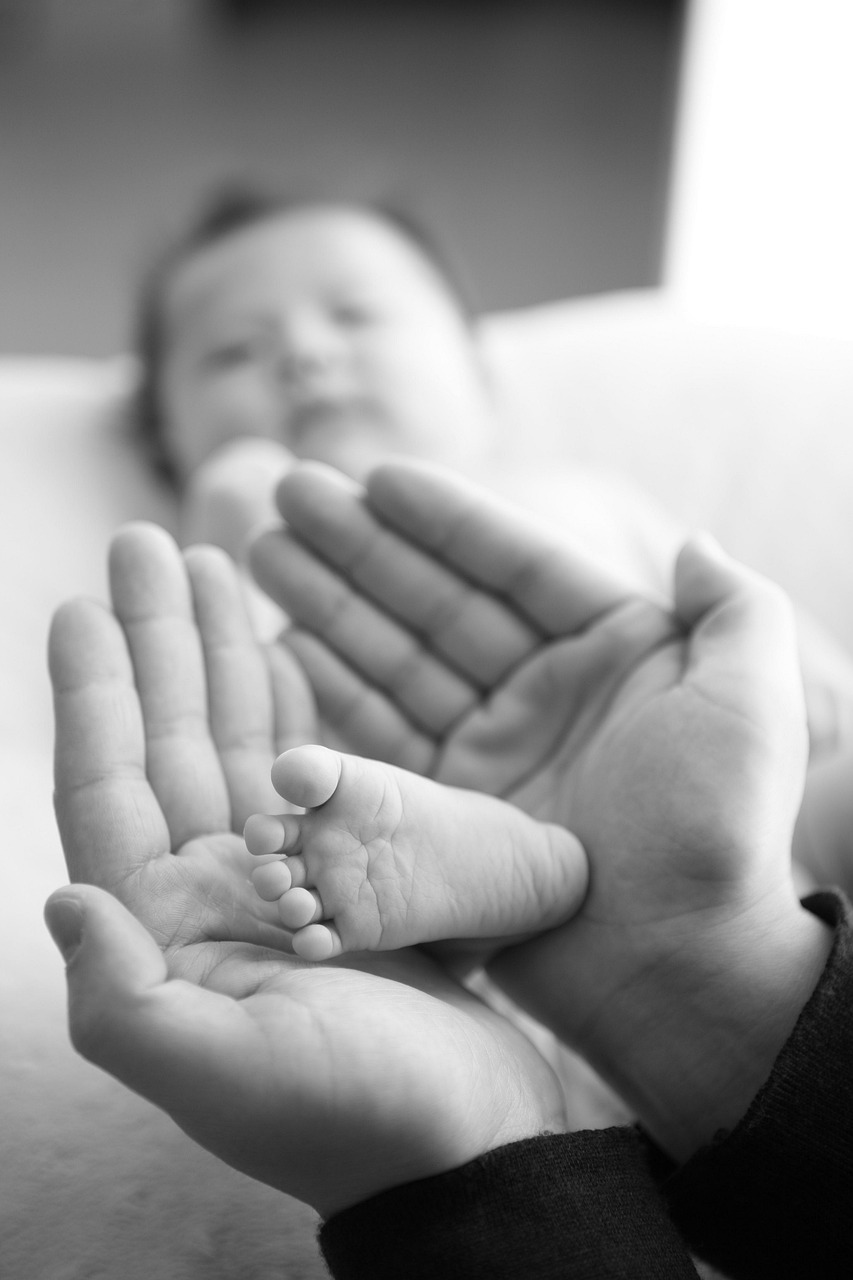 Volwassen handen die de voetjes van een pasgeboren baby vasthouden